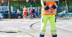 Man in Hi-Vis clothing standing on tram line observing